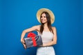 Smiling woman present gift box with red ribbon. Beauty woman isolated on blue studio background Royalty Free Stock Photo