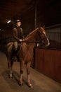 Smiling woman rancher riding out stable on horse