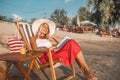 Smiling woman reading a book while sitting on deck chair Royalty Free Stock Photo