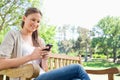 Smiling woman reading text message on a park bench Royalty Free Stock Photo