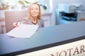 Smiling woman at the reception desk, office, notary office gives documents for signature