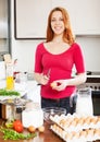 Smiling woman in red making omelette with eggs Royalty Free Stock Photo