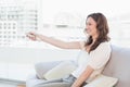 Smiling woman with remote control sitting on sofa Royalty Free Stock Photo