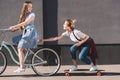 smiling woman riding bicycle and towing her female friend
