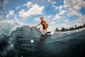 Smiling woman riding on wave sitting on surfboard and touching the water with her hand. Royalty Free Stock Photo