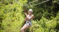 Smiling woman riding a zip line in a lush tropical forest Royalty Free Stock Photo