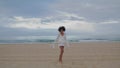 Smiling woman running ocean beach. Cheerful black haired girl dancing throwing Royalty Free Stock Photo