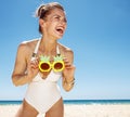 Smiling woman at sandy beach holding funky pineapple glasses