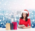 Smiling woman in santa hat with bags and tablet pc