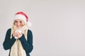 Smiling woman in Santa hat with cup of coffee, isolated on white. The girl is dressed in sweater, christmas cap and Royalty Free Stock Photo