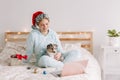 Smiling woman in Santa hat with cute puppy dog pet calling family friends on video call. Pet owner celebrating Christmas holiday Royalty Free Stock Photo