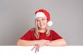 A smiling woman in a Santa hat rests her hands on an empty blank board