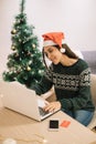 Smiling woman with Santa hat sitting at the laptop Royalty Free Stock Photo