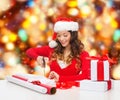 Smiling woman in santa helper hat packing gift box