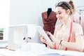 Smiling woman seamstress sitting and using tablet at work Royalty Free Stock Photo
