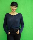 smiling woman with short hair standing against green wall.