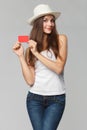 Smiling woman showing blank credit card in white t-shirt, isolated over gray background Royalty Free Stock Photo