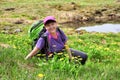 Smiling woman sits on blooming alpine lawn