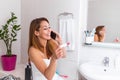 Smiling woman sitting in bathroom and holding positive pregnancy test and talking on her smart phone with the father to give him Royalty Free Stock Photo