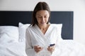 Smiling woman sitting on bed, looking at pregnancy test Royalty Free Stock Photo