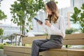 Smiling woman sitting on bench outdoor on the park using smartphone chatting social media Royalty Free Stock Photo