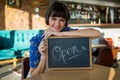 Smiling woman sitting in the coffee shop with a open sign Royalty Free Stock Photo