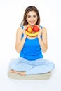 Smiling woman sitting on a floor in yoga pose, holding fruit sm
