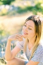 Smiling woman sitting on the grass touching her chin with her fingers