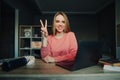 Smiling woman sitting at home at work with laptop, books and notebooks and looking at camera with smile on face shows gesture OK Royalty Free Stock Photo