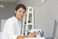 Smiling woman sitting with laptop and making notes during video call or online lesson at home Royalty Free Stock Photo