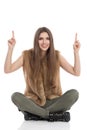 Smiling Woman Sitting Legs Crossed And Pointing Up Royalty Free Stock Photo