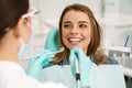 Smiling woman sitting in medical chair while dentist fixing her teeth