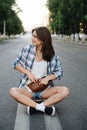 Smiling woman sitting in the middle of an empty city road, hand in fanny pack