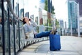 Smiling woman sitting outside with mobile phone and bags Royalty Free Stock Photo