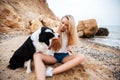 Smiling woman sitting and playing with dog on beach Royalty Free Stock Photo