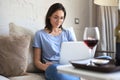 Smiling woman sitting on sofa with laptop computer and chating with friends