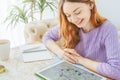 Smiling woman sitting at table looking at tablet with map of travel route. Royalty Free Stock Photo