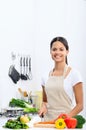 Smiling woman slicing vegetables in a kitchen