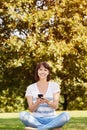 Smiling woman with smart phone sitting in grass