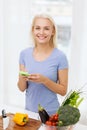 Smiling woman with smartphone cooking vegetables