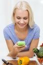 Smiling woman with smartphone cooking vegetables