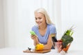 Smiling woman with smartphone cooking vegetables