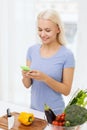 Smiling woman with smartphone cooking vegetables