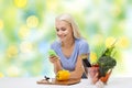 Smiling woman with smartphone cooking vegetables