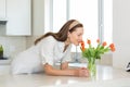 Smiling Woman Smelling Flowers In Kitchen