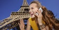 Smiling woman speaking on a cell phone and hand waving in Paris