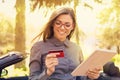 Smiling woman standing by her car making online payment on her tablet computer outside on a summer day Royalty Free Stock Photo