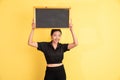 smiling woman standing holding blackboard above head