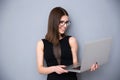 Smiling woman standing with laptop over gray background Royalty Free Stock Photo