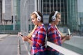 Smiling woman standing outside with smart phone and headphones Royalty Free Stock Photo